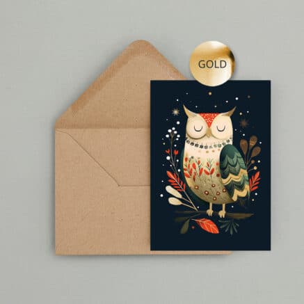 Weihnachtskarte mit liebevoll illustrierter Eule auf dunkelblauem Hintergrund. Florale Muster, Blätter, Sterne und goldene Veredelung geben dem Eulenmotiv einen festlichen Look. Die Karte liegt vor einem braunen Kraftpapier Umschlag.